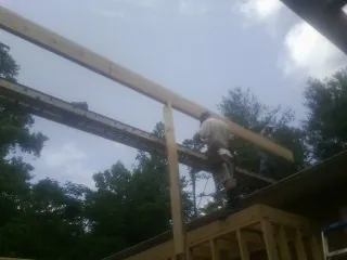 Carpenter setting a ridge beam over a new addition frame — Ice Dam Removal by Roofing Brothers in Danciger