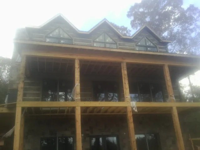Dormers and porch framing on a large log home under construction — Roof Coating work by our crew in Danciger