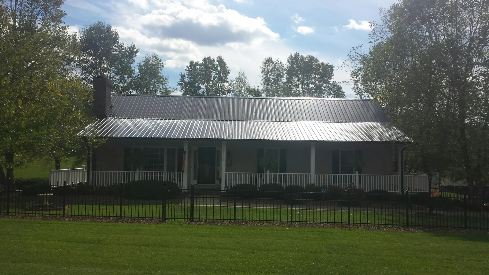 Gray metal roof on a brick ranch with a full width front porch — Gutter Guard Installation work by our crew in Danciger
