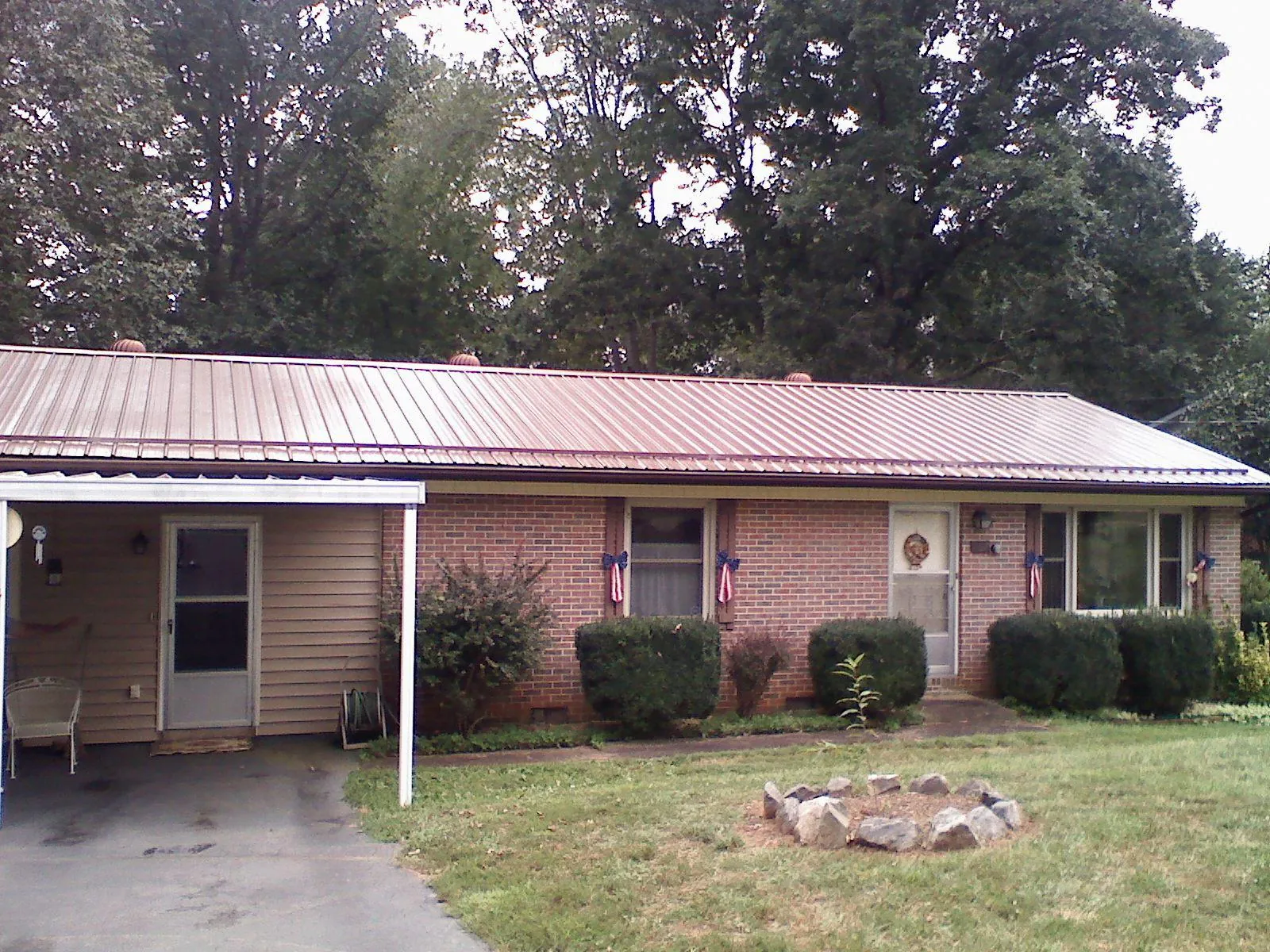 Bronze metal roof and carport on a brick ranch home — Roof Repair work by our crew in Danciger